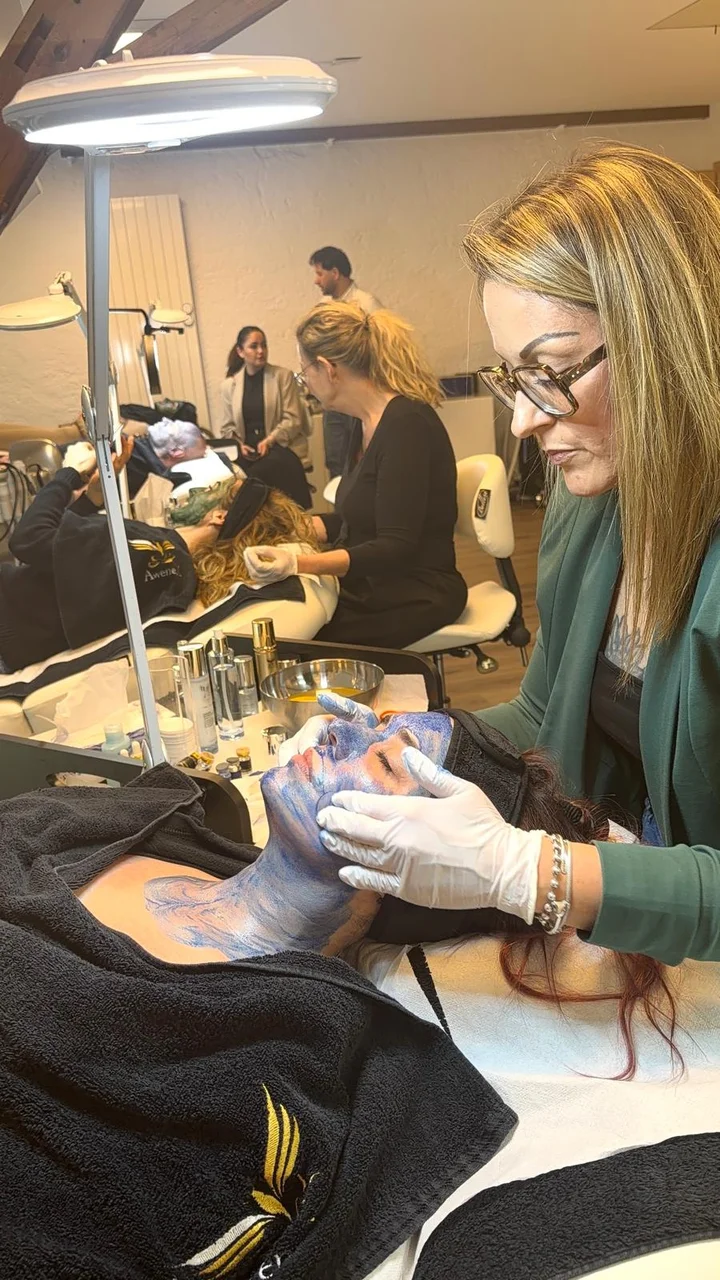 Una partecipante si esercita in un trattamento cosmetico viso con i guanti durante una formazione